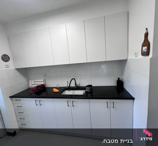 מטבח מודרני עם ארונות לבנים ומשטח עבודה שחור